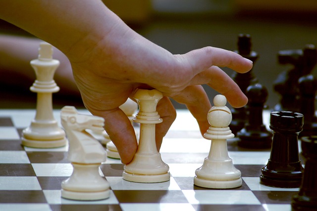 Hand picking up a Chess piece on a Chess board