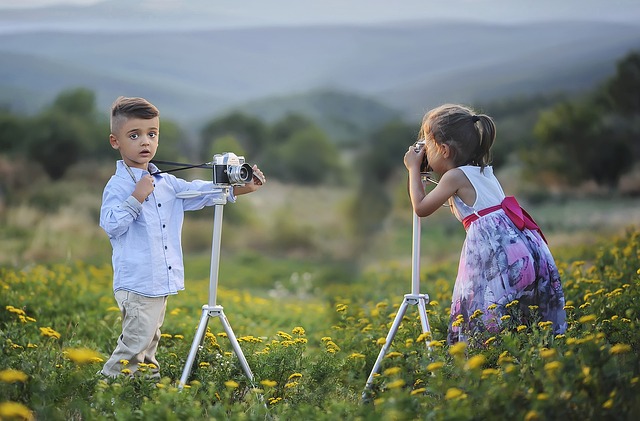 Two children taking photographs of each other in a field