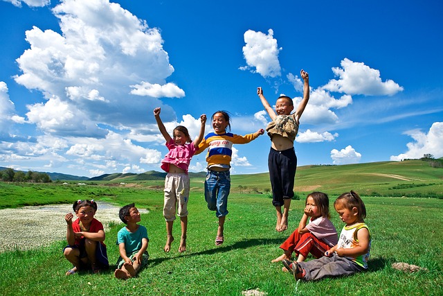 Children playing in a field. Bright blue sky, bright green grass.