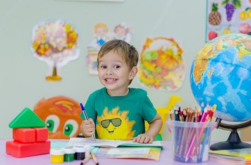 Little boy smiling at the camera while coloring