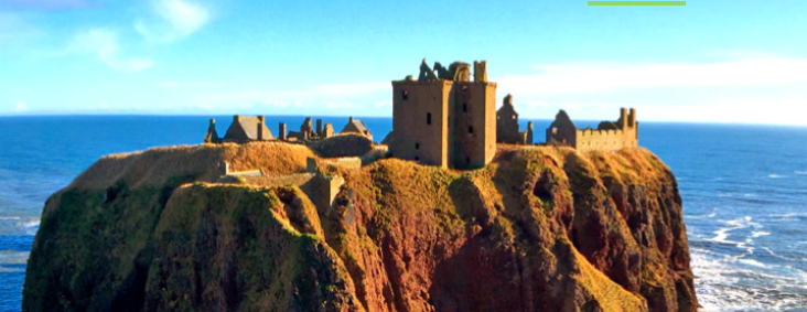 A castle on a cliff against a bright blue sky.