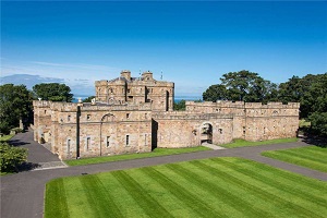 A castle with a green striped lawn and blue sky behind.